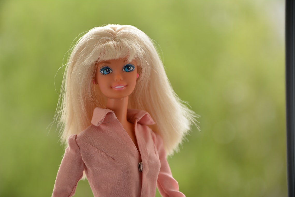 barbie doll in pink shirt with green outdoors behind