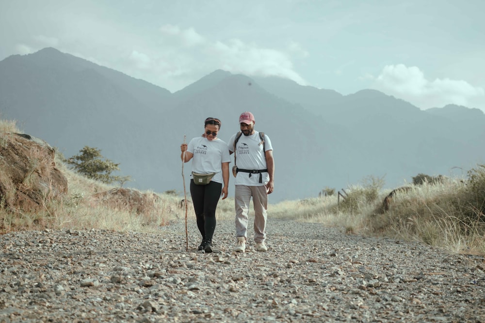 man and woman holding hands while walking on rocky ground during daytime