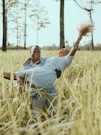 man in white polo shirt and brown pants lying on brown grass field during daytime