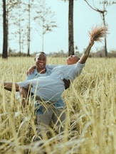 man in white polo shirt and brown pants lying on brown grass field during daytime