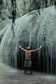 man in black shorts standing in front of waterfalls