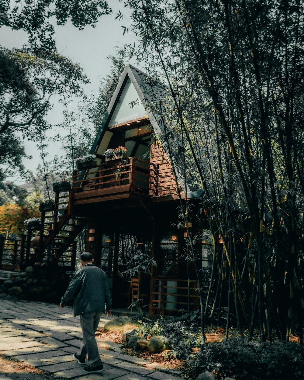 man in gray jacket standing near brown wooden house during daytime