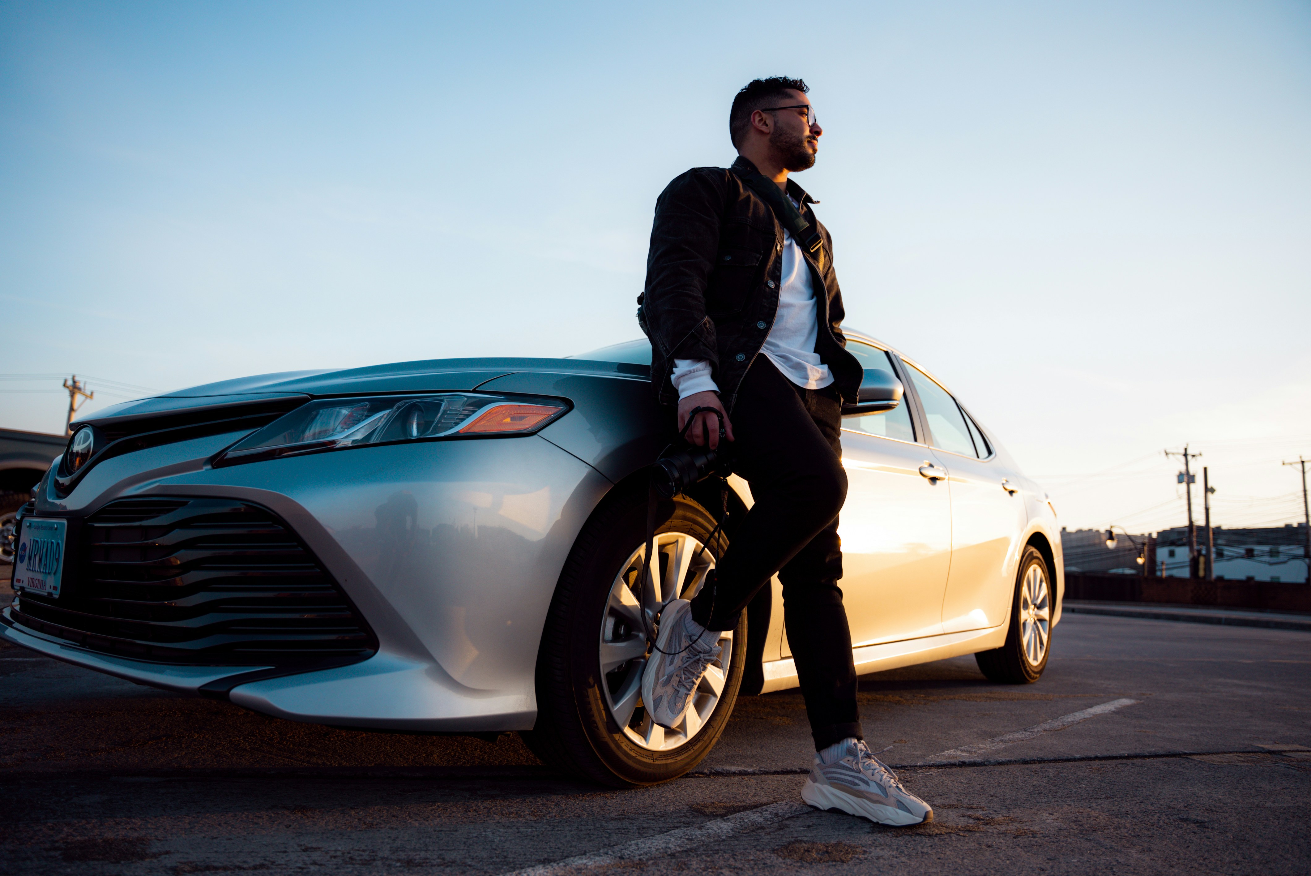 man in black jacket and black pants leaning on silver car