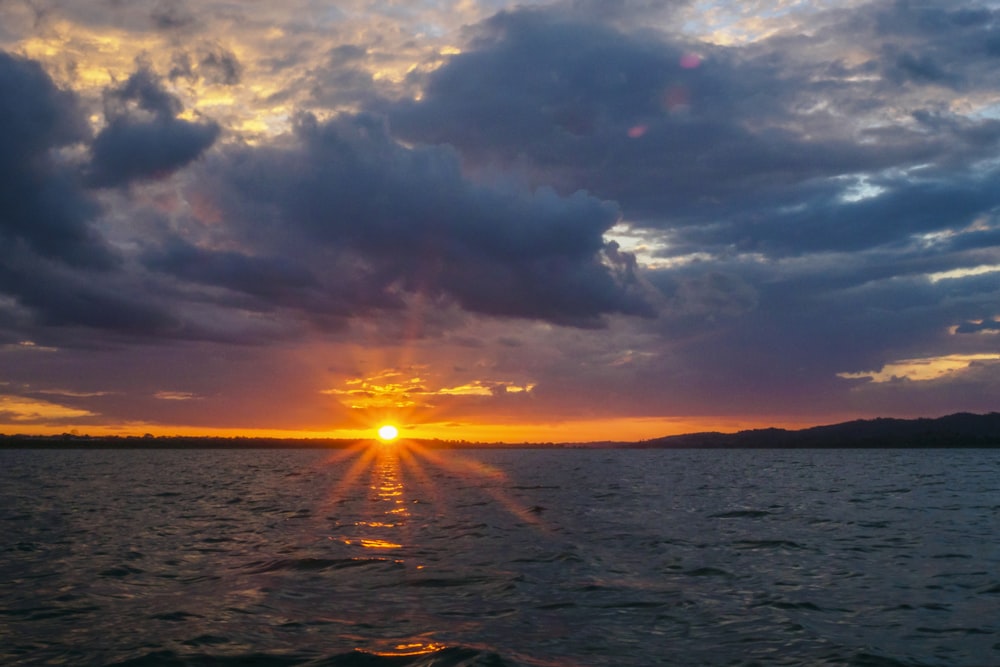 body of water under cloudy sky during sunset