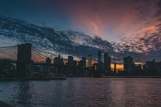 An artistic bridge made of light connecting two city skylines at dusk.