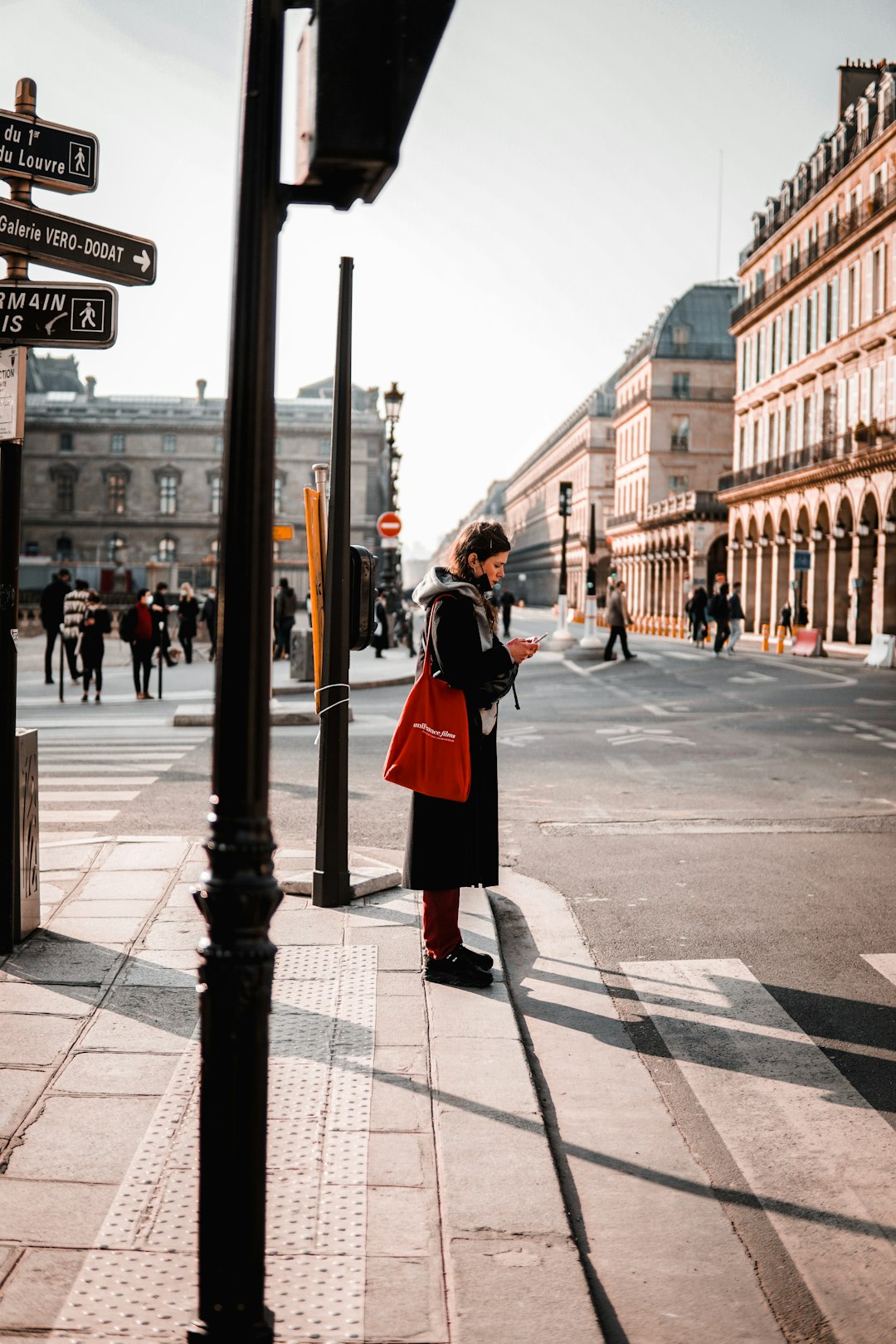 woman in black coat standing on sidewalk during daytime