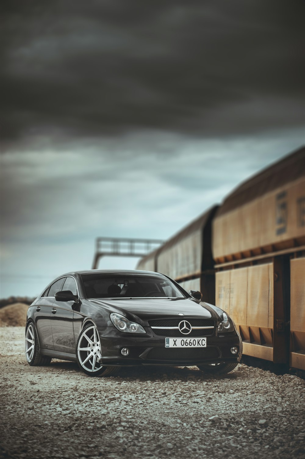 Mercedes Benz Coupé negro estacionado junto a una valla de madera marrón durante el día