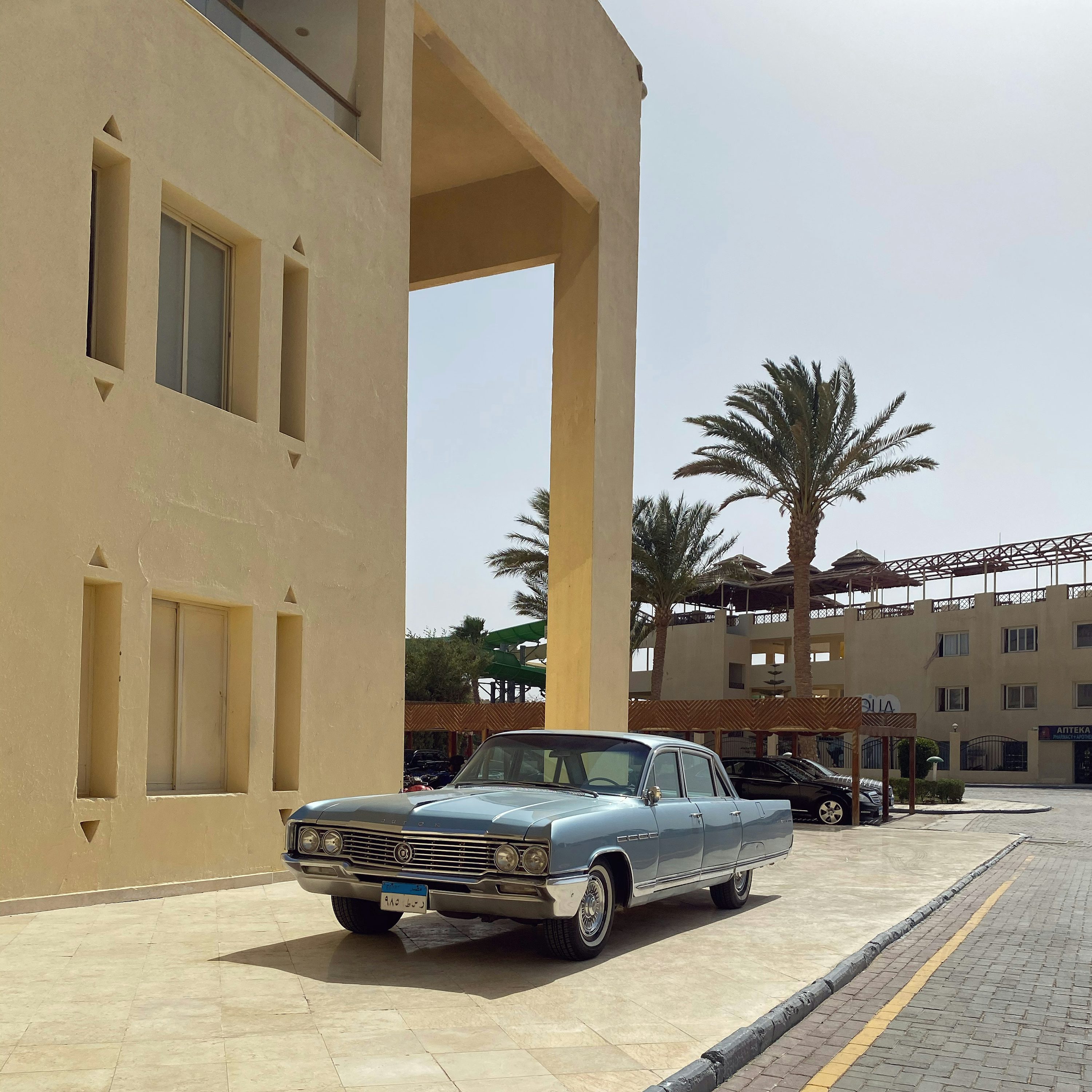 black sedan parked beside beige concrete building during daytime