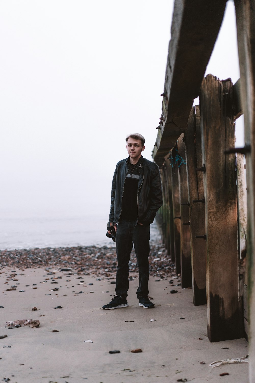 man in black jacket standing on beach during daytime