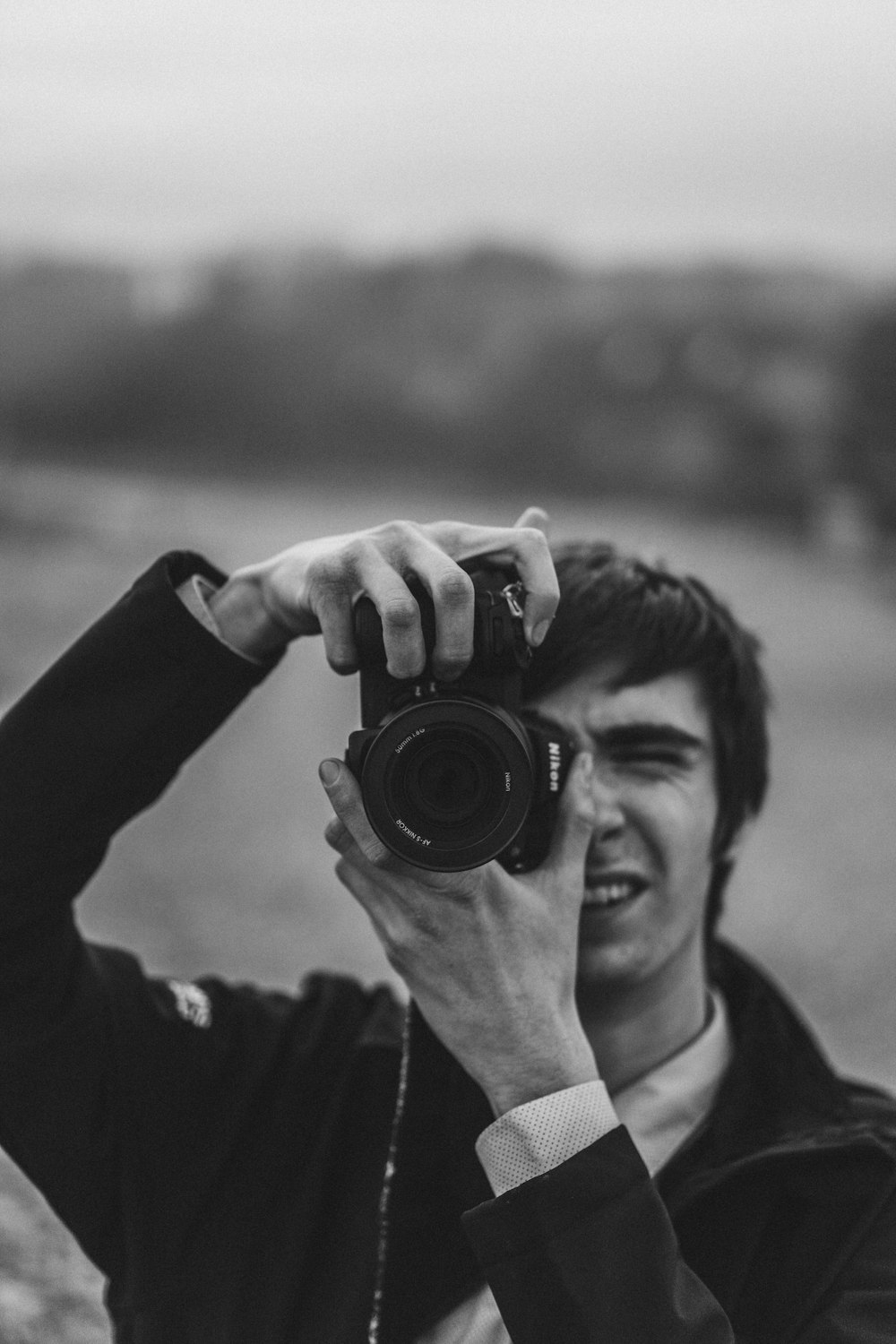 Foto in scala di grigi di un uomo che tiene la macchina fotografica