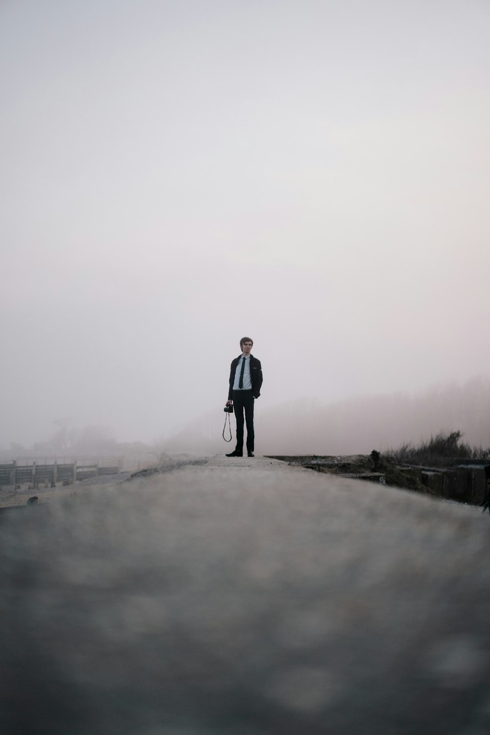 man in black jacket standing on gray concrete road