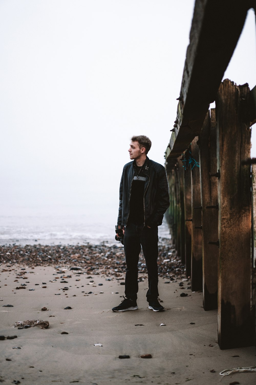 man in black jacket standing on beach during daytime