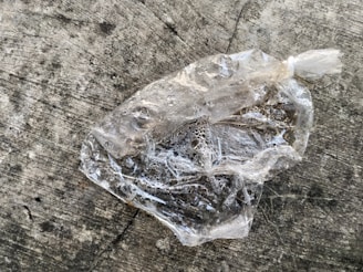 A waterproof foldable bag hanging by a faucet with water droplets on its surface.