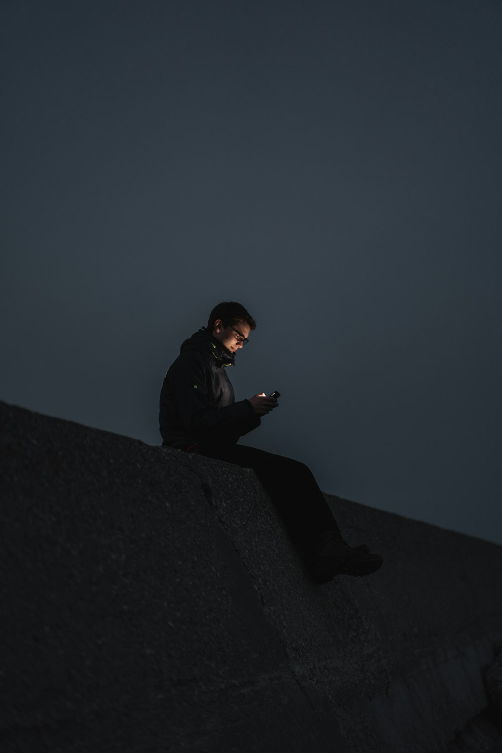 man in black jacket sitting on the edge of a building