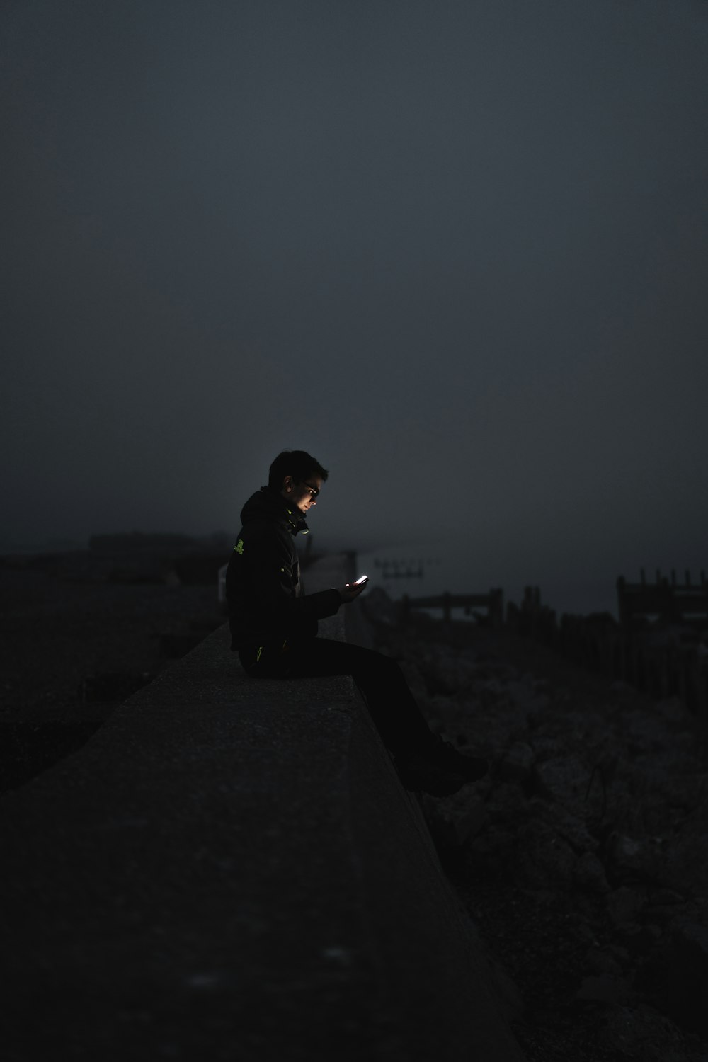 homme en veste noire assis sur le sol pendant la nuit