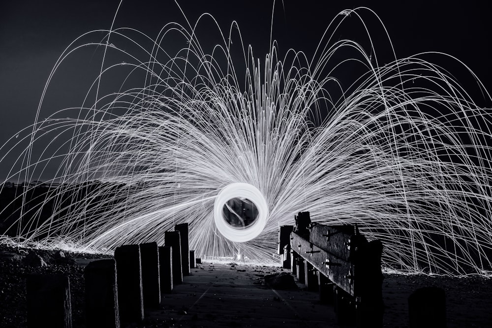 steel wool photography of a man standing on a bridge
