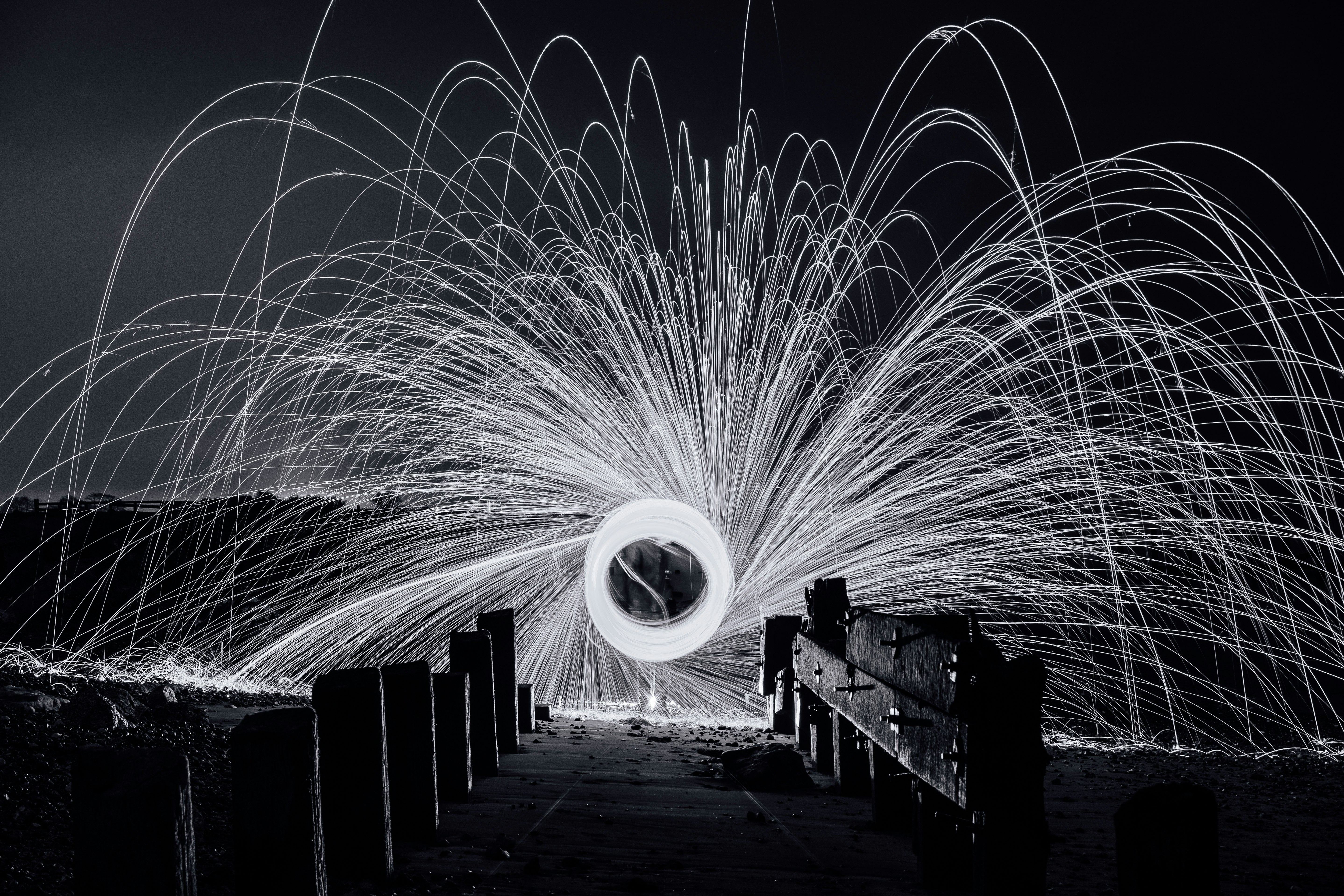 steel wool photography of a man standing on a bridge