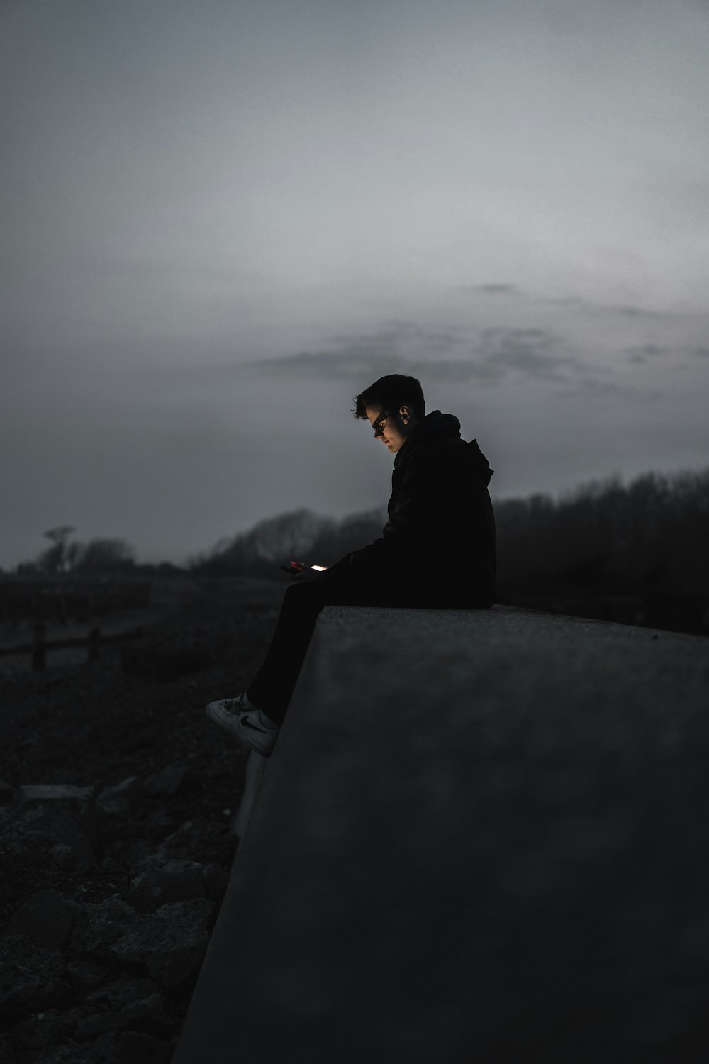 man in black hoodie sitting on gray concrete bench during daytime