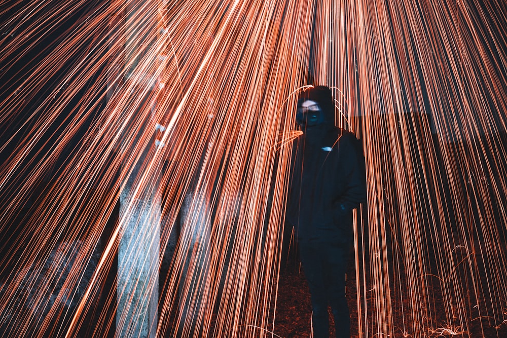 man in black jacket standing in front of brown and blue lights