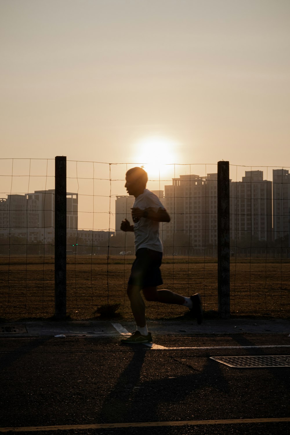 man in white t-shirt and black shorts standing on gray concrete pavement during daytime