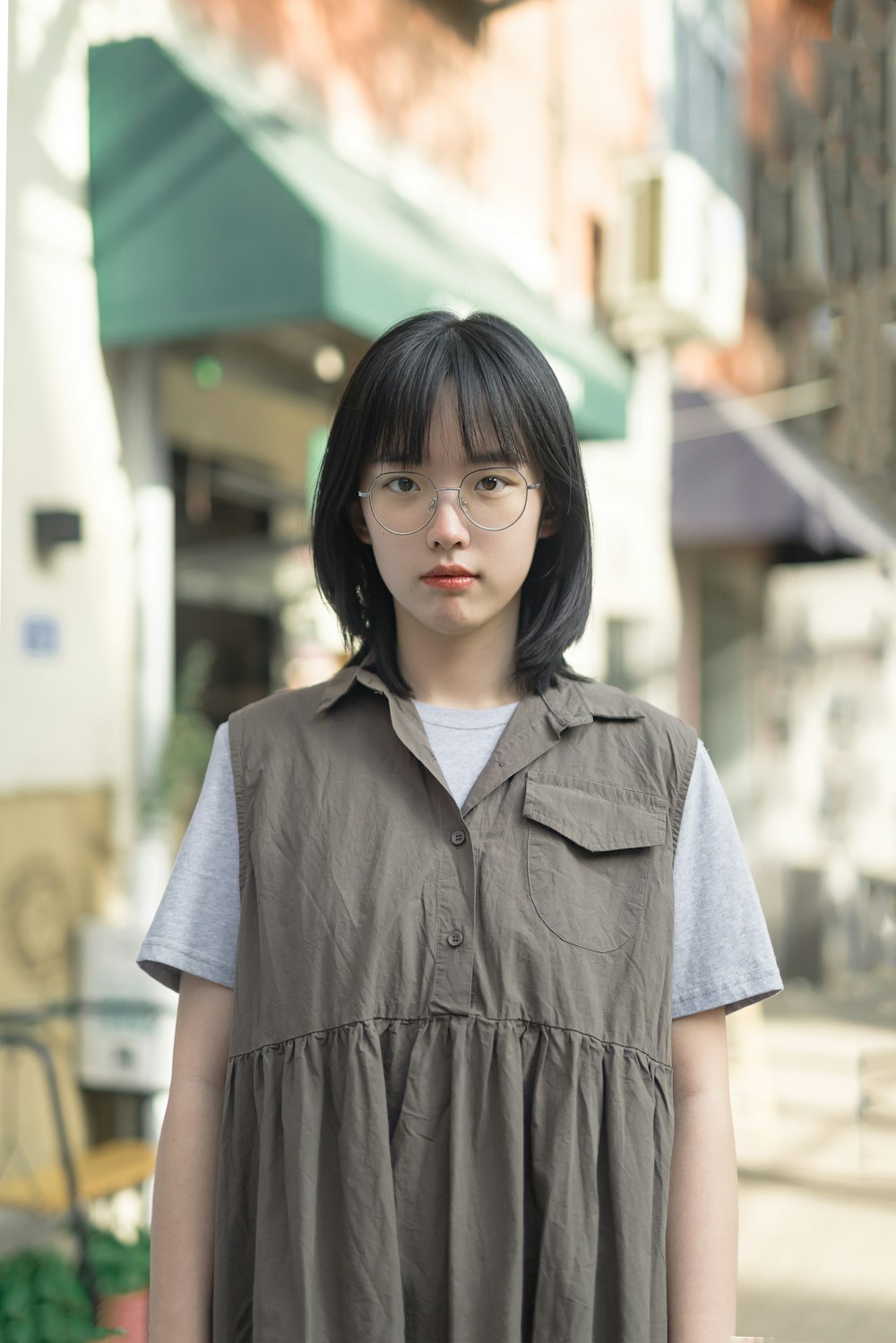 woman in blue button up shirt standing near building during daytime