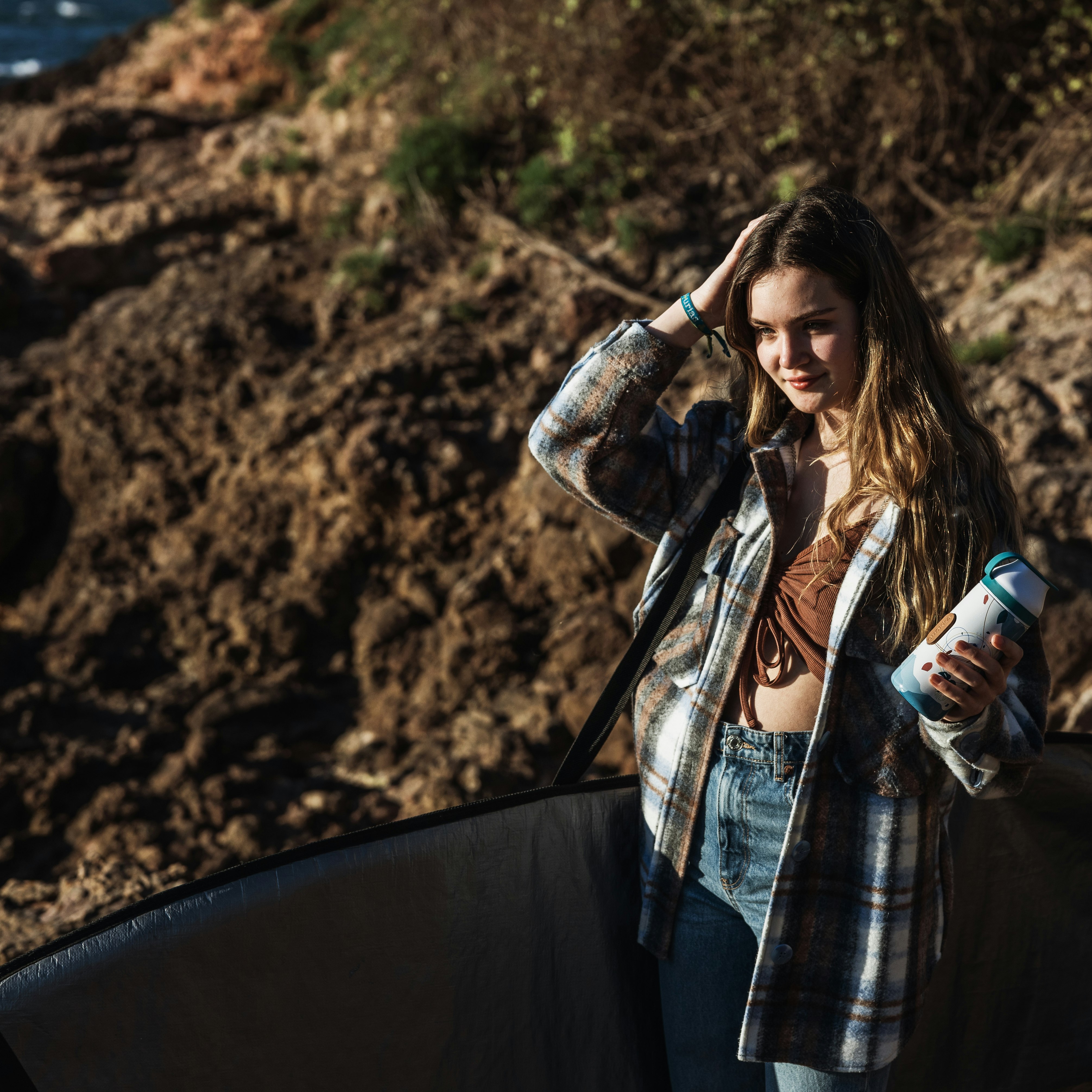 woman in black and white plaid coat holding clear plastic bottle