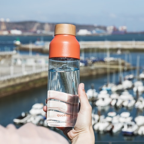 person holding orange and clear glass bottle