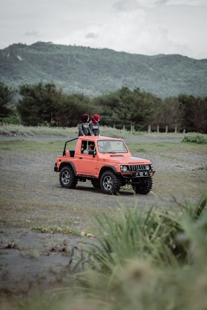 red jeep wrangler on dirt road during daytime