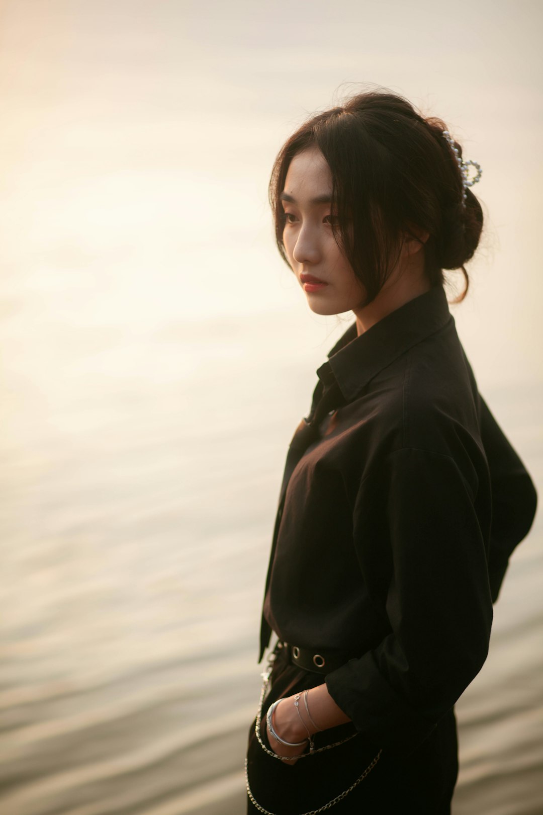 woman in black coat standing near body of water during daytime