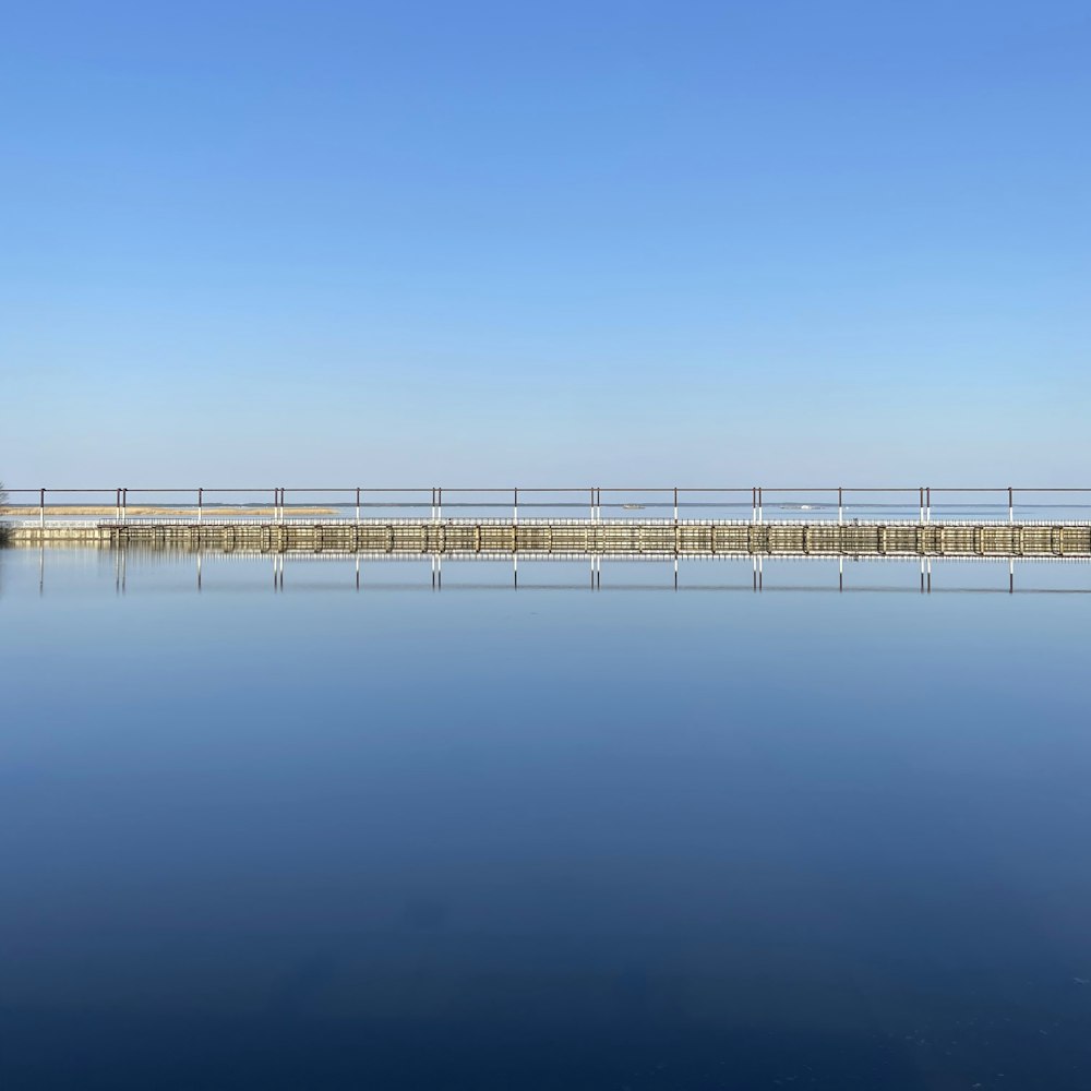 white wooden dock on calm water under blue sky during daytime