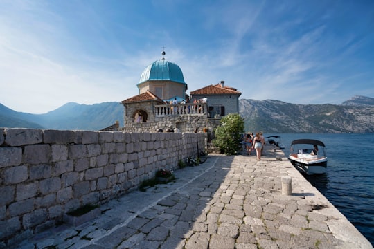 people walking on sidewalk near brown concrete building during daytime in Our Lady of the Rocks Montenegro