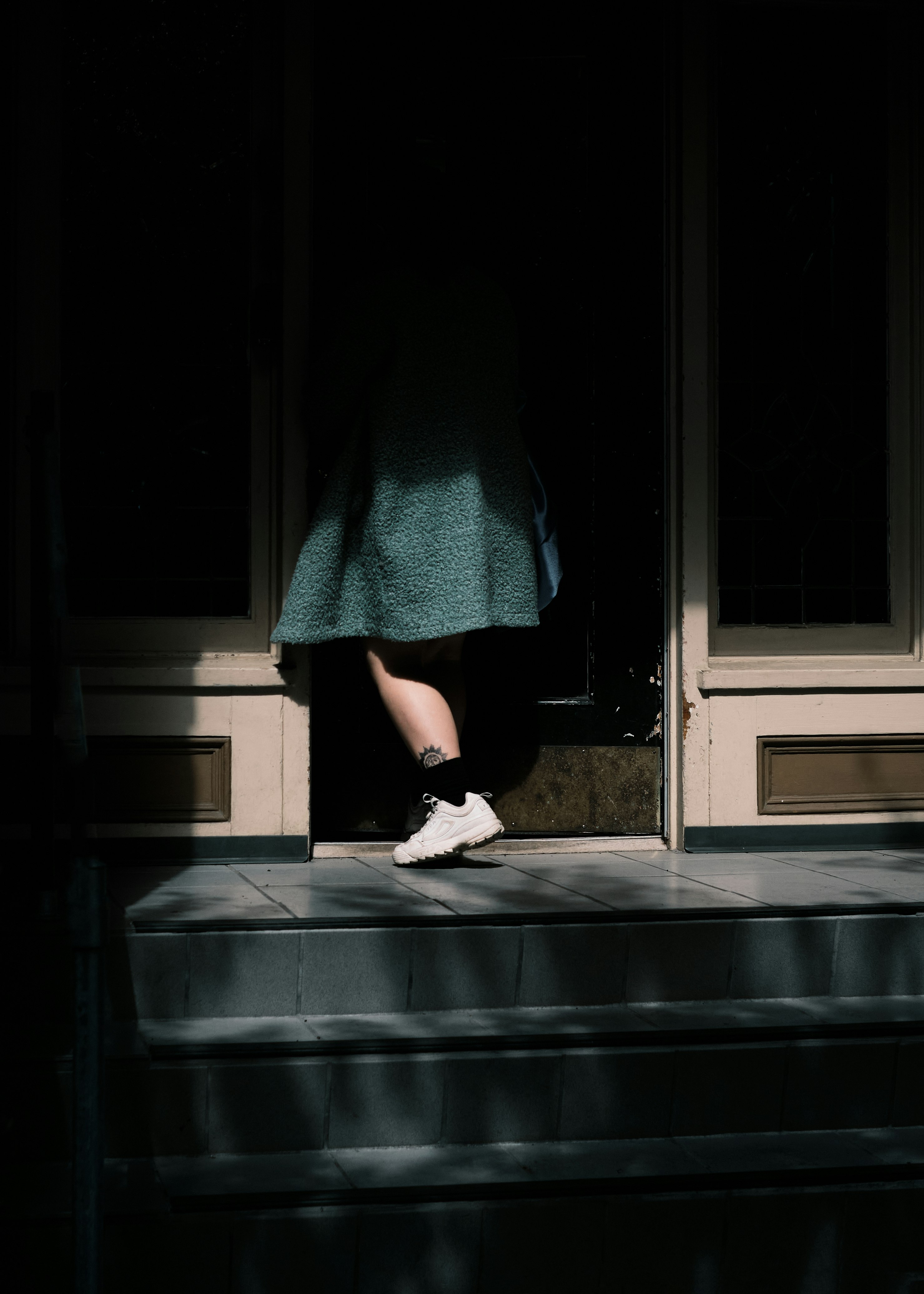 person in black skirt and white sneakers standing on black staircase