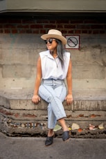 woman in white sleeveless shirt and blue denim jeans sitting on concrete stairs
