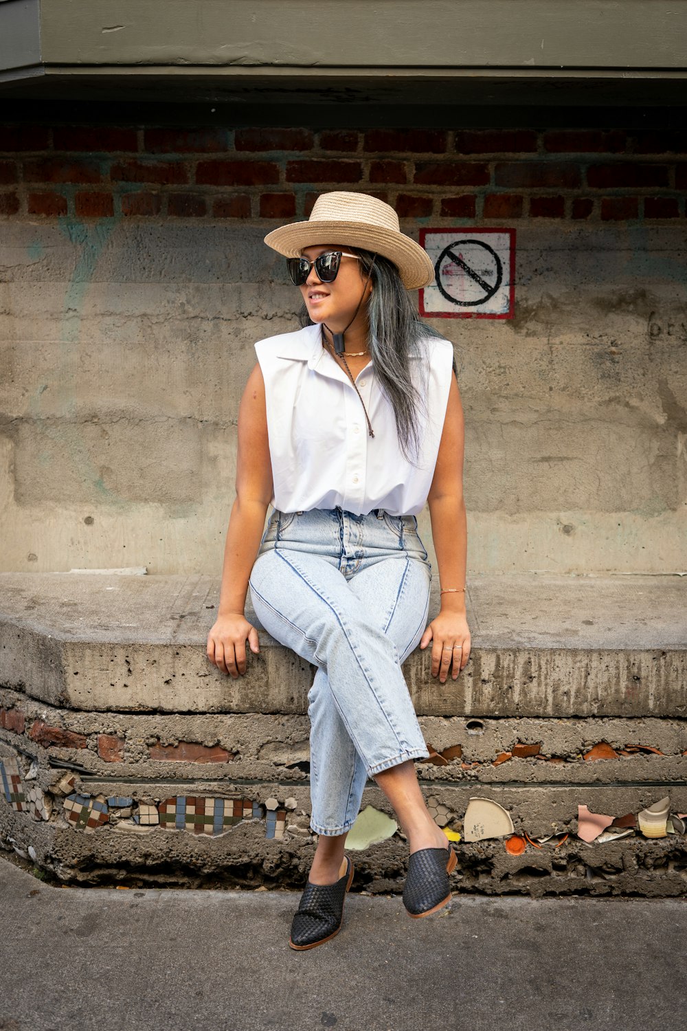 woman in white sleeveless shirt and blue denim jeans sitting on concrete stairs