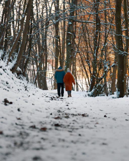 Fern and Lavarre walking hand in hand through a snowy Salt Lake City park.