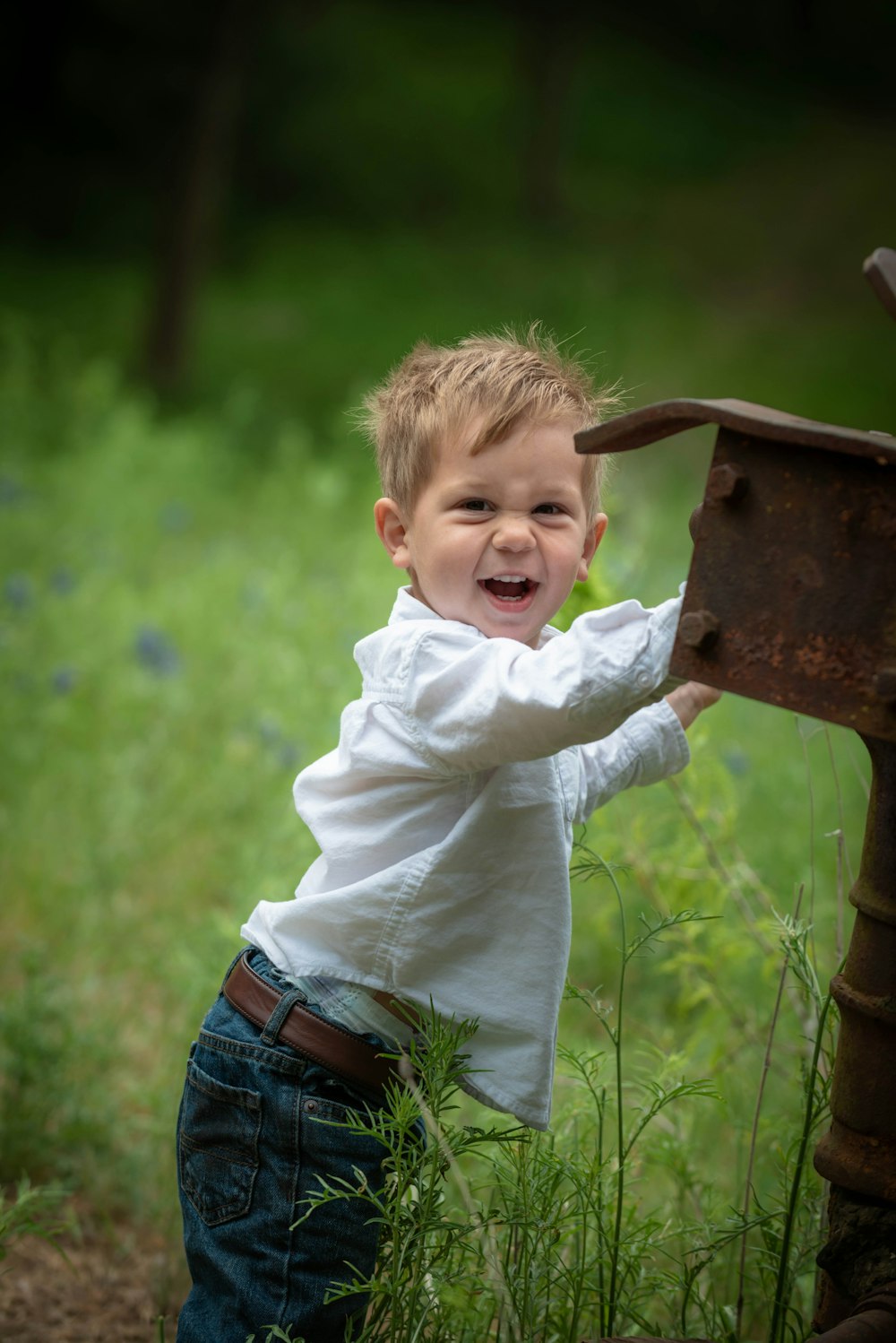 boy in white long sleeve shirt and blue denim jeans standing on brown wooden bench during