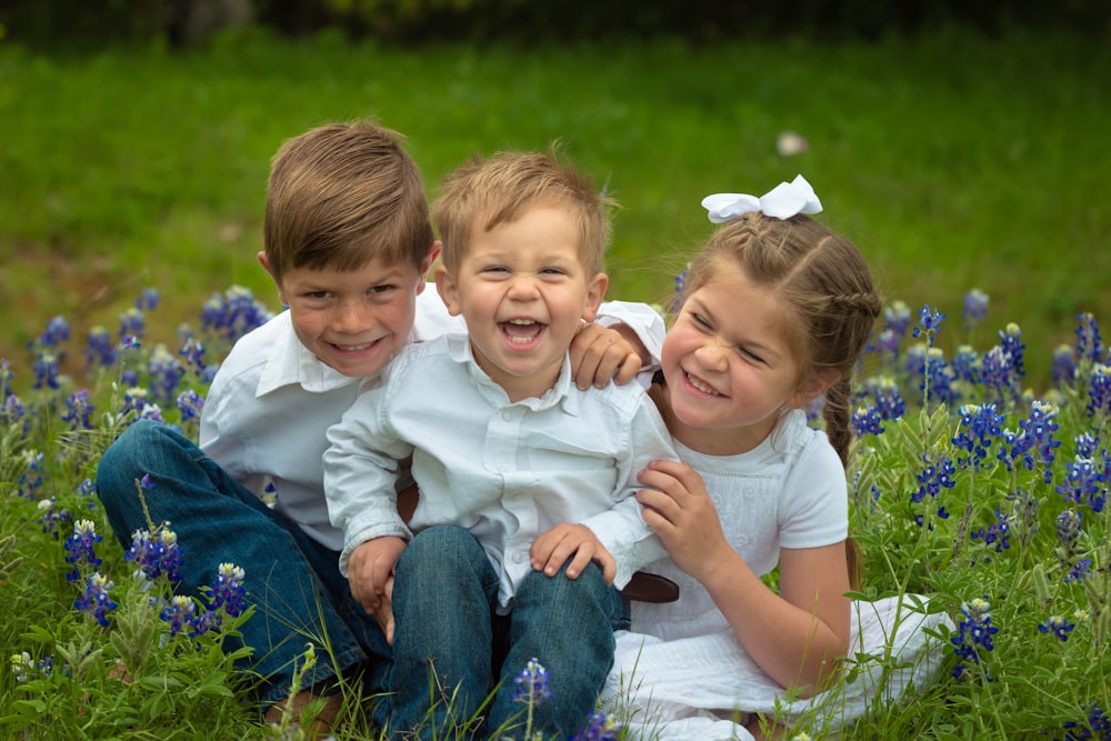 2 boys sitting on grass field during daytime