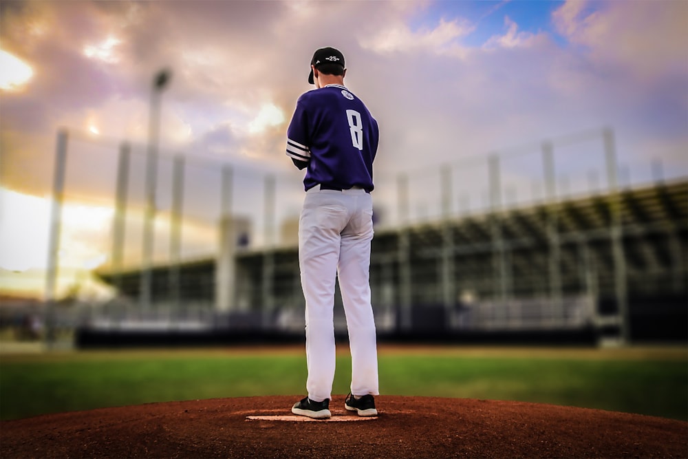 man in black and white baseball jersey standing on brown field during daytime