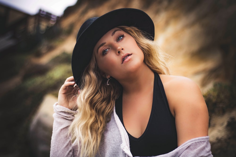 woman in black tank top and gray cardigan wearing black hat