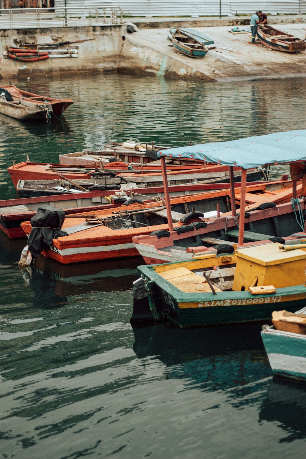 man in black jacket sitting on brown wooden boat dock during daytime