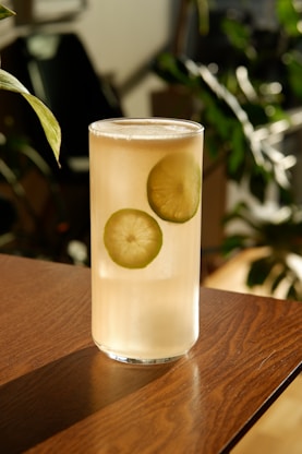 clear drinking glass with yellow liquid on brown wooden table
