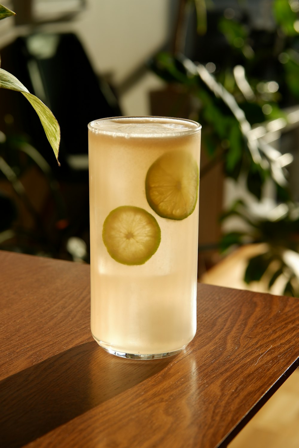 clear drinking glass with yellow liquid on brown wooden table