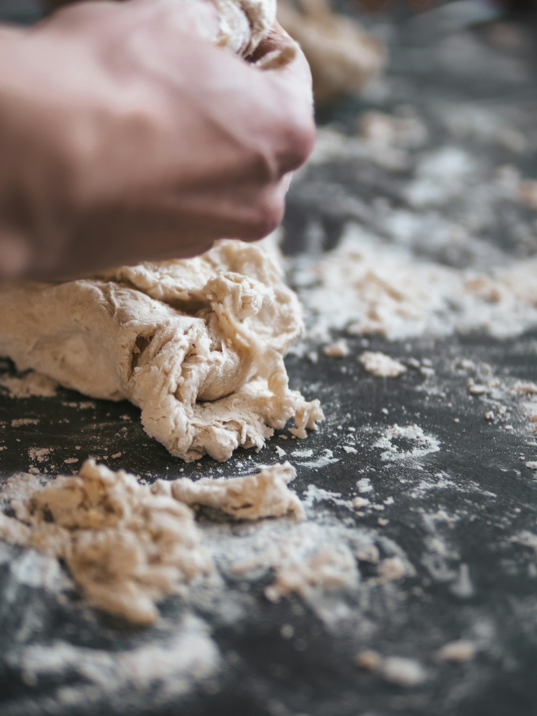 person holding white dough on black table