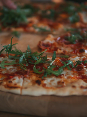 Close-up of a wood-fired pizza with bubbling cheese and fresh basil leaves
