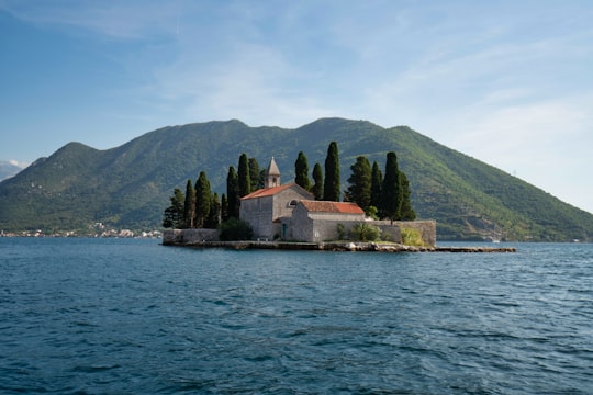 brown and white concrete building near body of water during daytime in Our Lady of the Rocks Montenegro