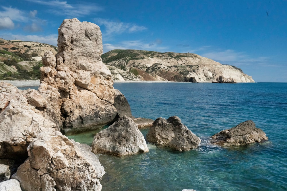 brown rocky mountain beside blue sea under blue sky during daytime