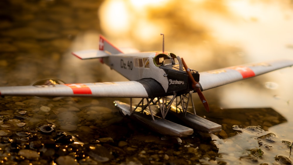 white and red plane toy on brown and black rock