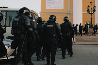 group of police men in black uniform standing on gray concrete floor during daytime