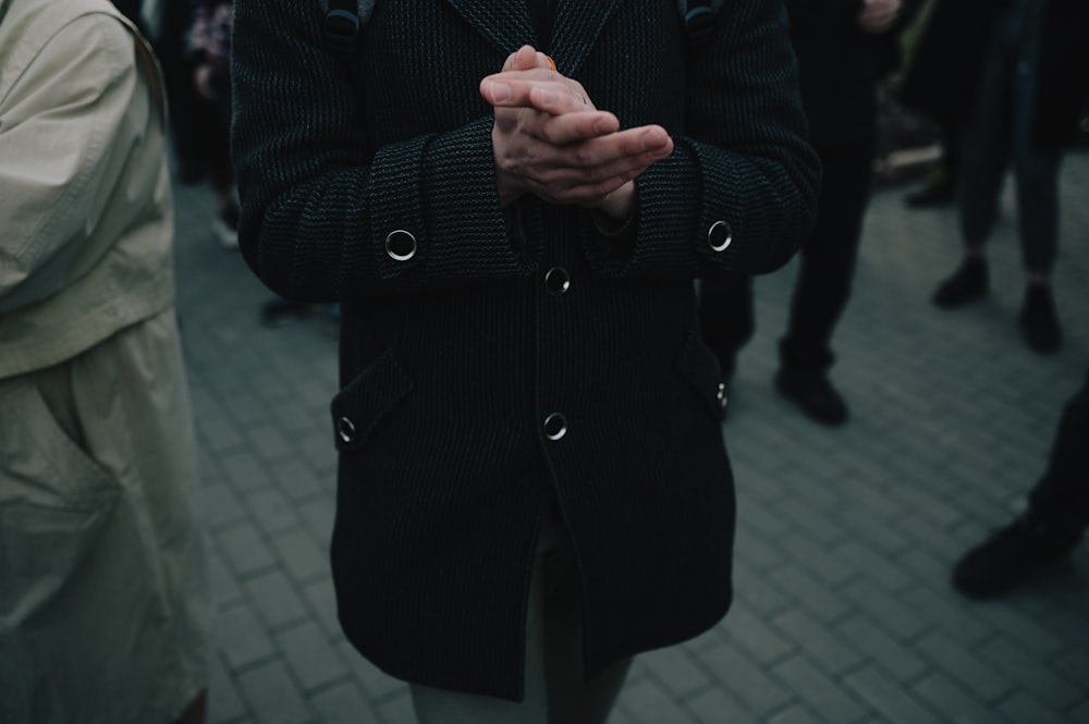 man in black coat standing on gray concrete floor