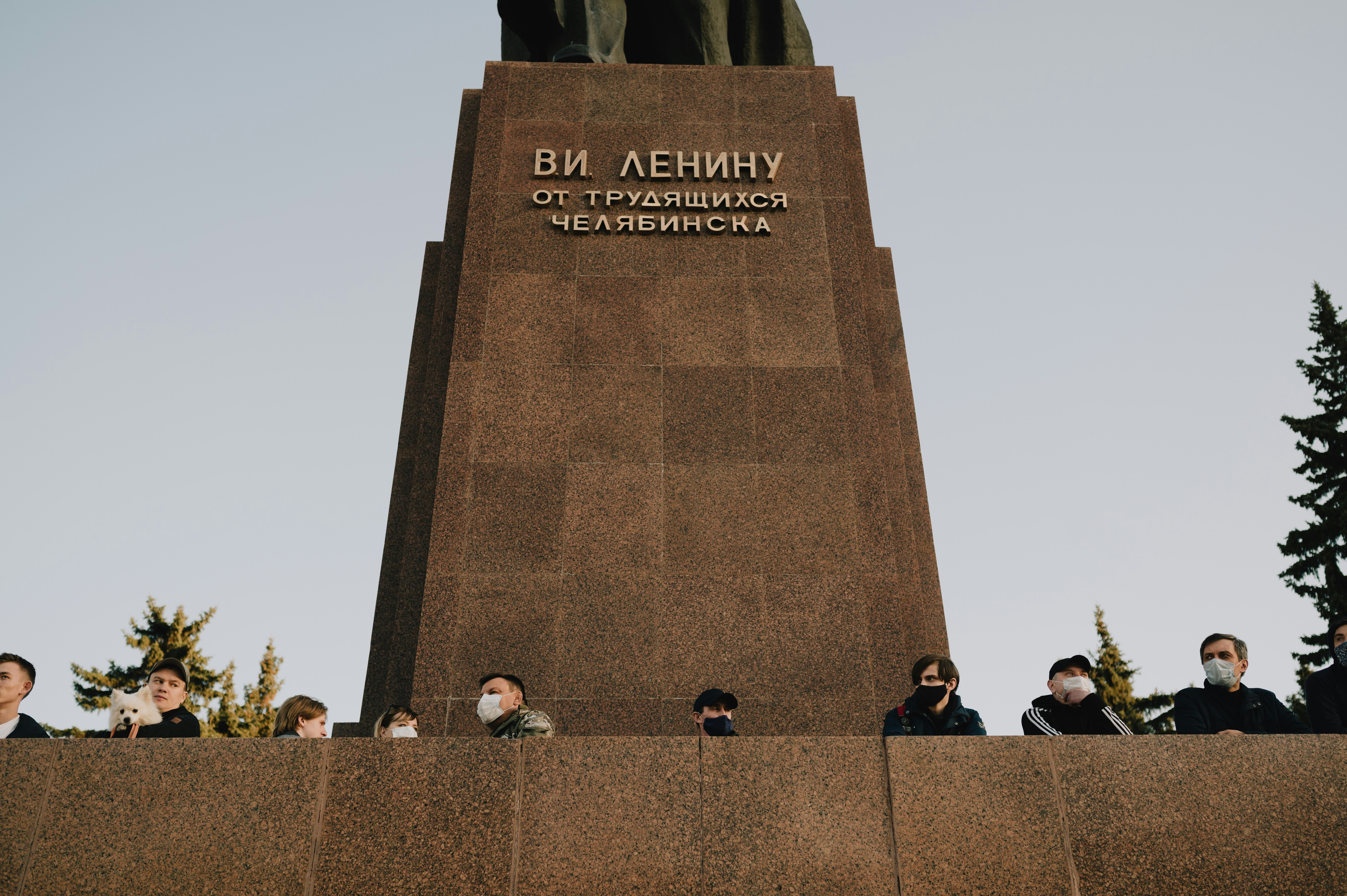 people sitting on brown concrete bench near gray concrete monument during daytime